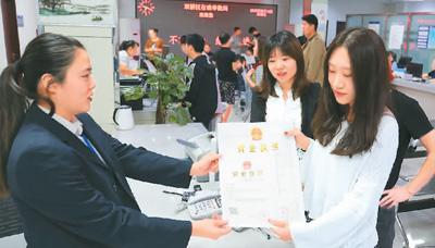 河北省承德市網(wǎng)絡(luò)代購經(jīng)營者陳晨(右)從工作人員手中接過帶有統(tǒng)一社會(huì)信用代碼的營業(yè)執(zhí)照。 劉環(huán)宇攝(人民圖片)