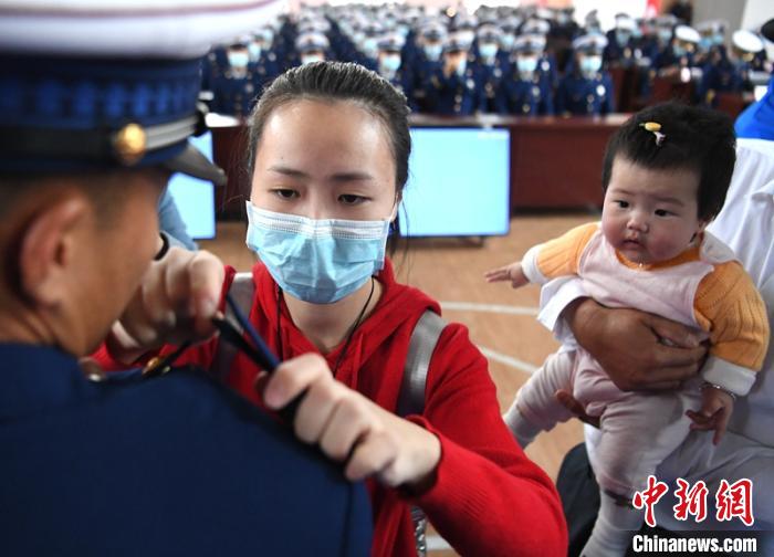新消防員楊振的妻子彭莉與女兒現(xiàn)場見證丈夫加入“火焰藍”的神圣時刻?！⒅铱?攝