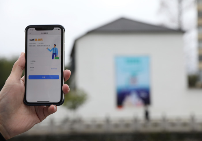 在浙江省杭州市臨安區(qū)天目山鎮(zhèn)，一名居民在“杭州健康碼”海報上掃碼申領(lǐng)個人二維碼。新華社發(fā)
